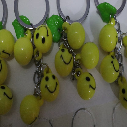 Bright Yellow Smiley Face Ball Keychain with Green Leaf Accent - Durable Plastic Design. - Abid Cart