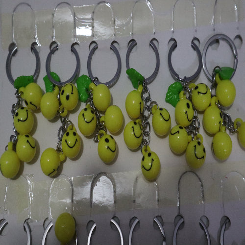 Bright Yellow Smiley Face Ball Keychain with Green Leaf Accent - Durable Plastic Design. - Abid Cart