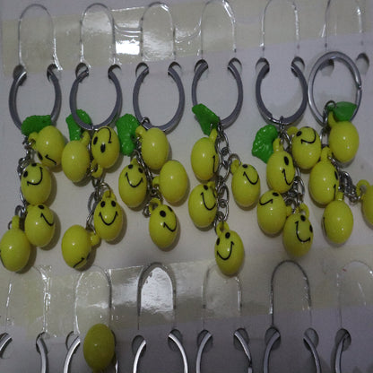 Bright Yellow Smiley Face Ball Keychain with Green Leaf Accent - Durable Plastic Design. - Abid Cart